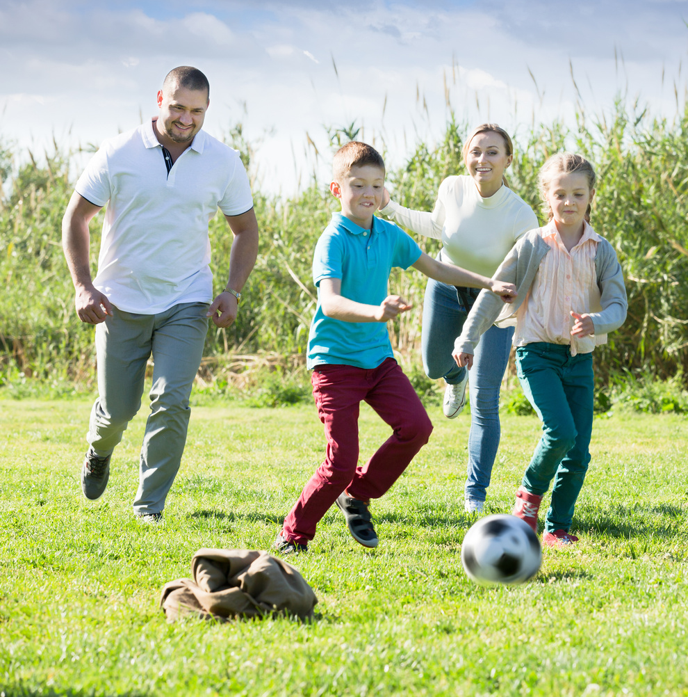 Cheerful parents with two kids playing soccer